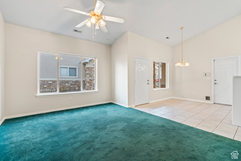 Unfurnished room with ceiling fan with notable chandelier, lofted ceiling, and light carpet
