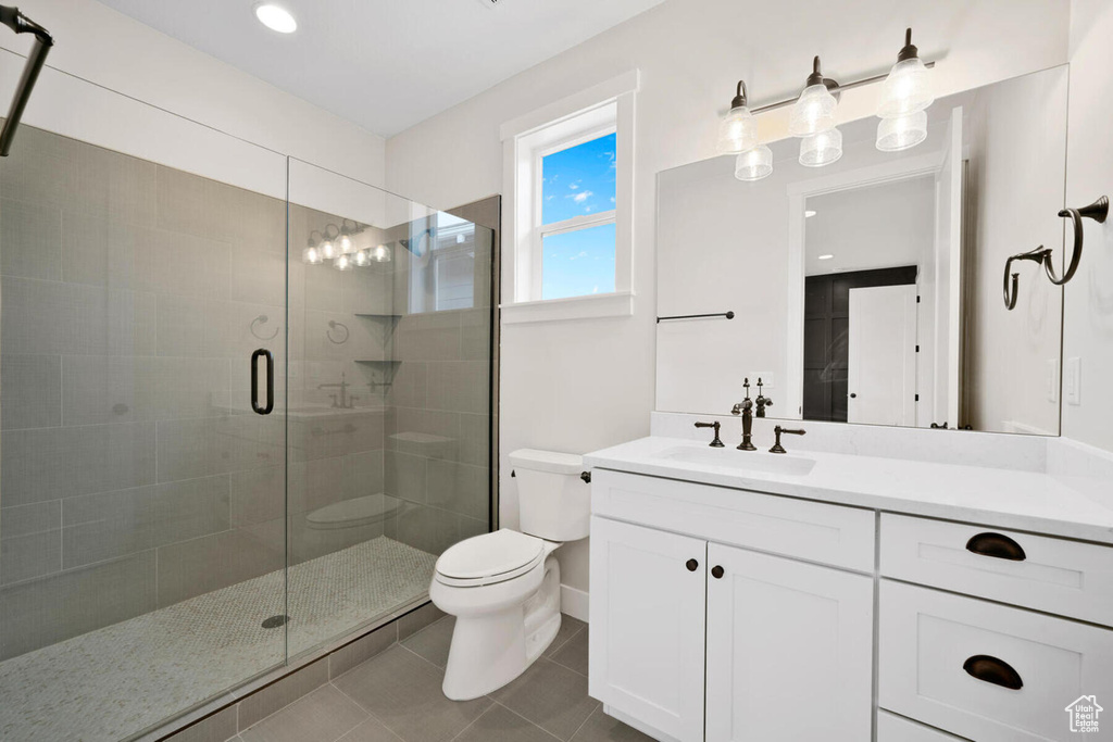 Bathroom with vanity with extensive cabinet space, tile floors, toilet, and walk in shower