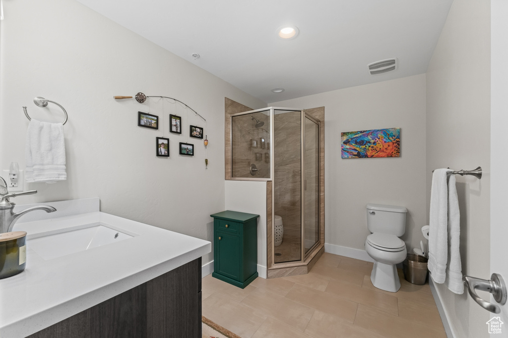 Bathroom featuring vanity, toilet, tile flooring, and a shower with shower door