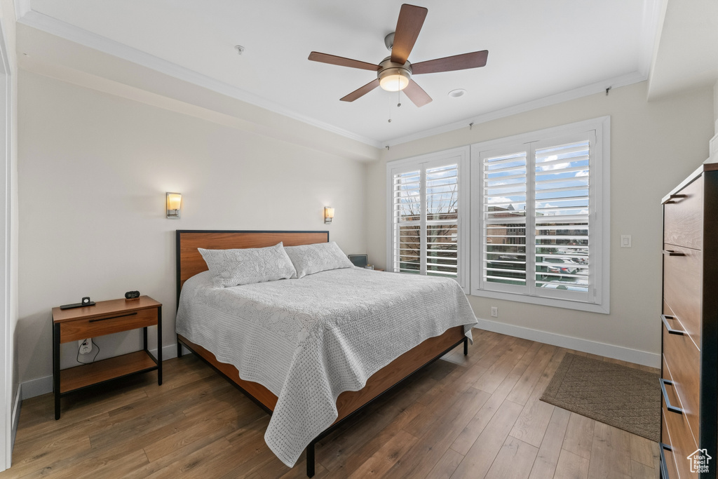 Bedroom with dark hardwood / wood-style flooring, crown molding, and ceiling fan