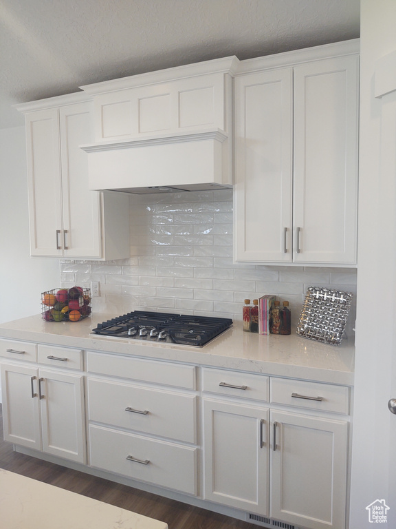 Kitchen featuring backsplash, dark hardwood / wood-style flooring, white cabinetry, and black gas stovetop