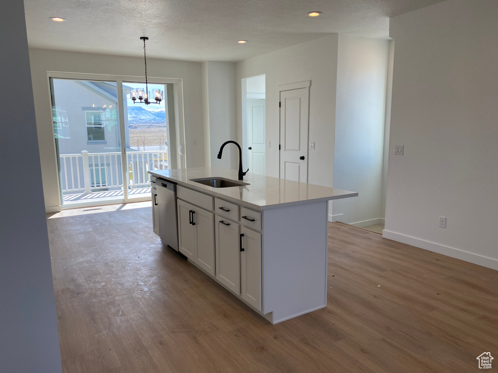 Kitchen featuring hardwood / wood-style flooring, a chandelier, dishwasher, sink, and decorative light fixtures