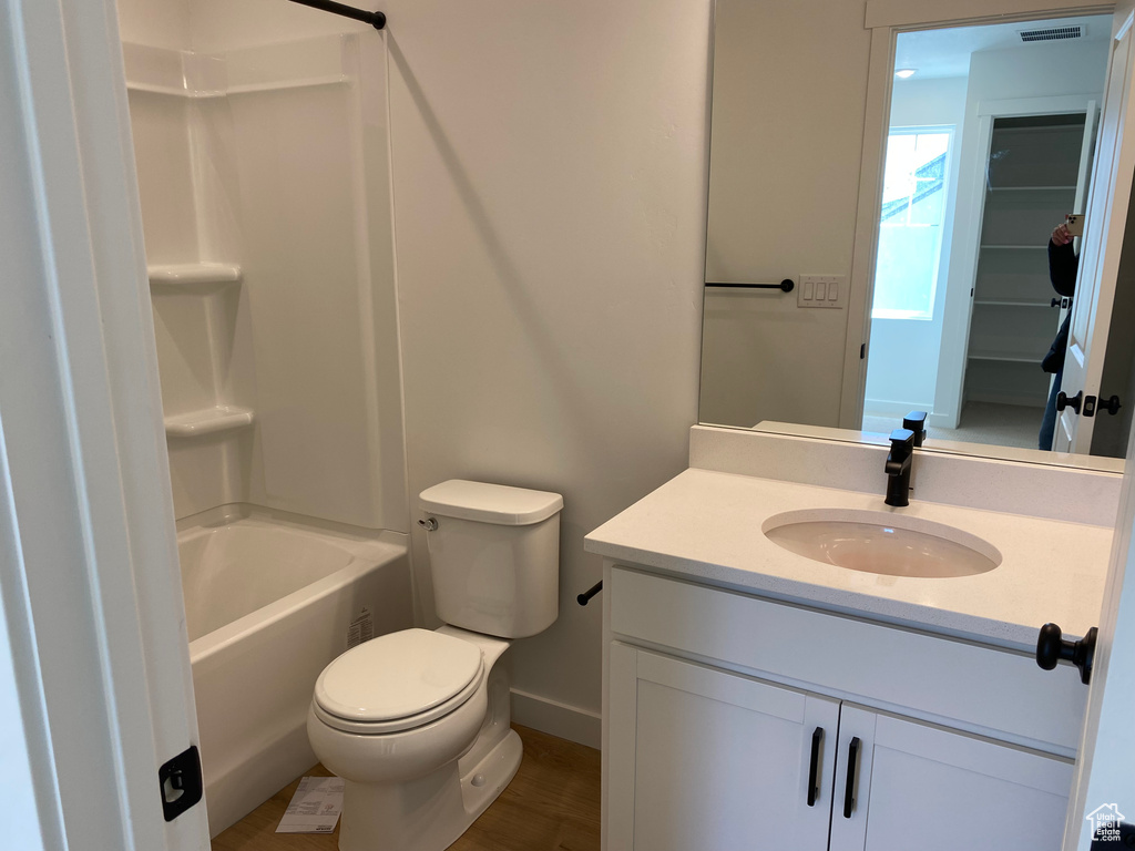 Full bathroom featuring wood-type flooring, toilet, vanity with extensive cabinet space, and shower / bathtub combination