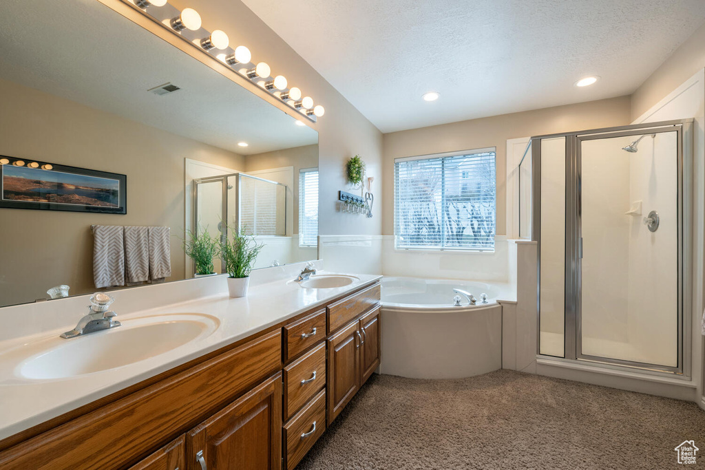 Bathroom with independent shower and bath, a textured ceiling, and dual vanity