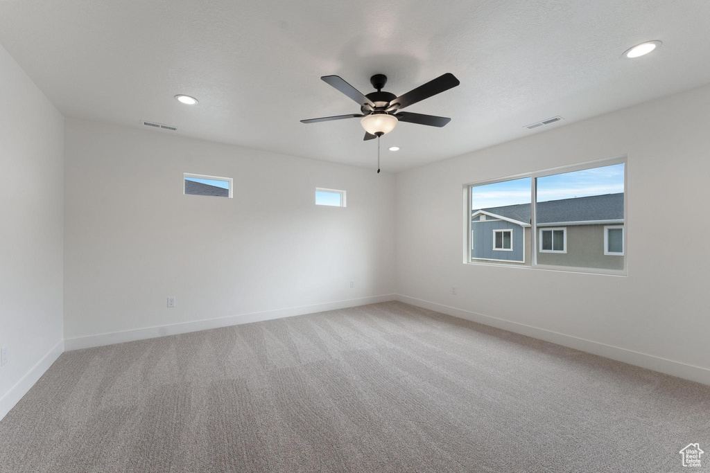 Carpeted spare room with a healthy amount of sunlight and ceiling fan