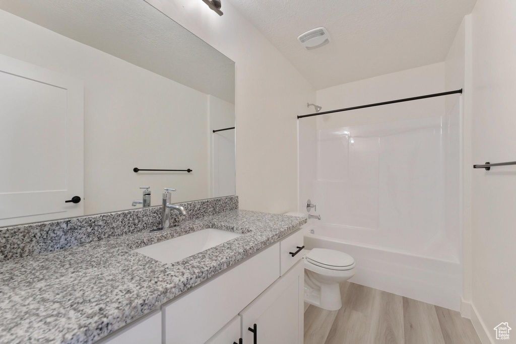 Full bathroom with wood-type flooring, bathing tub / shower combination, toilet, and vanity