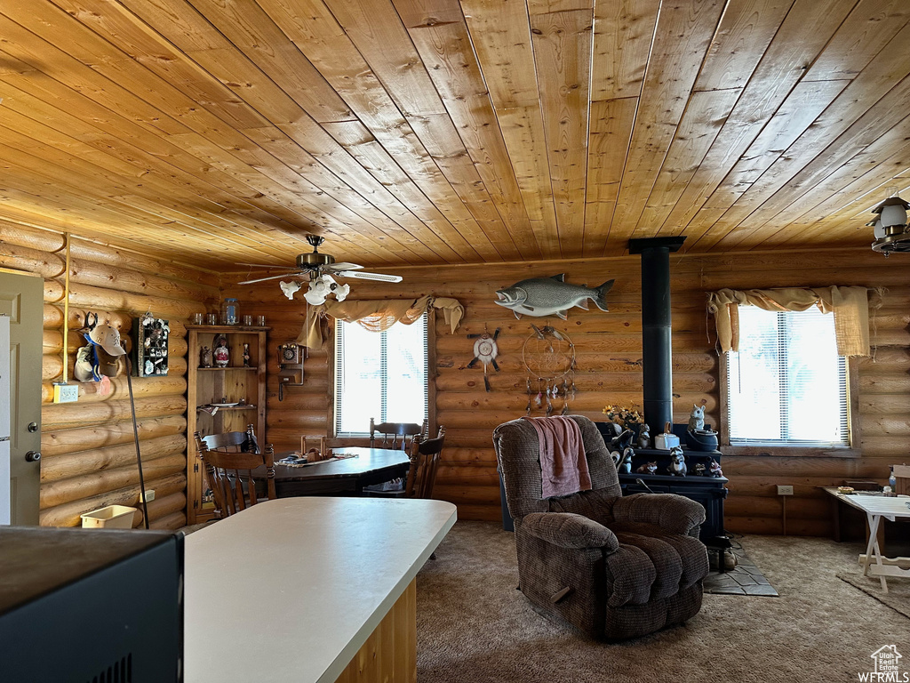 Interior space featuring dark colored carpet, rustic walls, ceiling fan, and wood ceiling