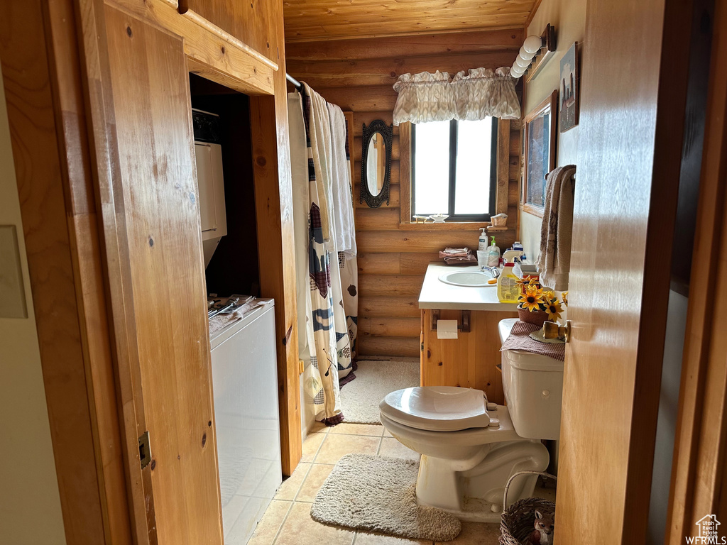 Bathroom featuring log walls, toilet, vanity, and tile flooring