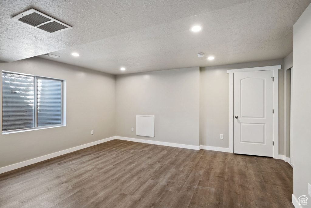 Empty room featuring a textured ceiling and dark hardwood / wood-style flooring