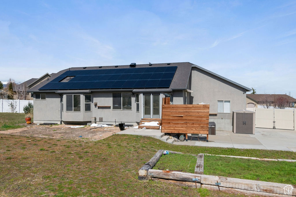 Back of house with a lawn and solar panels
