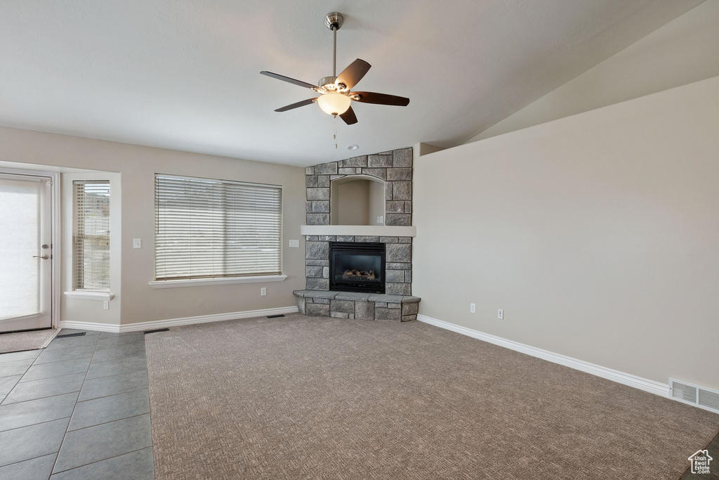 Unfurnished living room with vaulted ceiling, a fireplace, ceiling fan, and light tile floors
