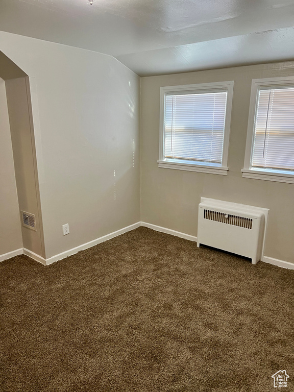 Spare room with dark colored carpet and radiator