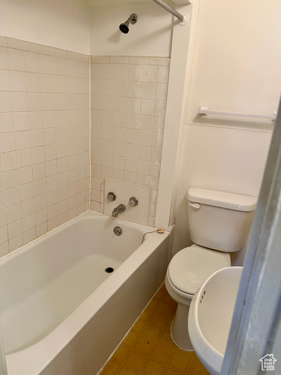 Bathroom with tile flooring, tiled shower / bath, and toilet