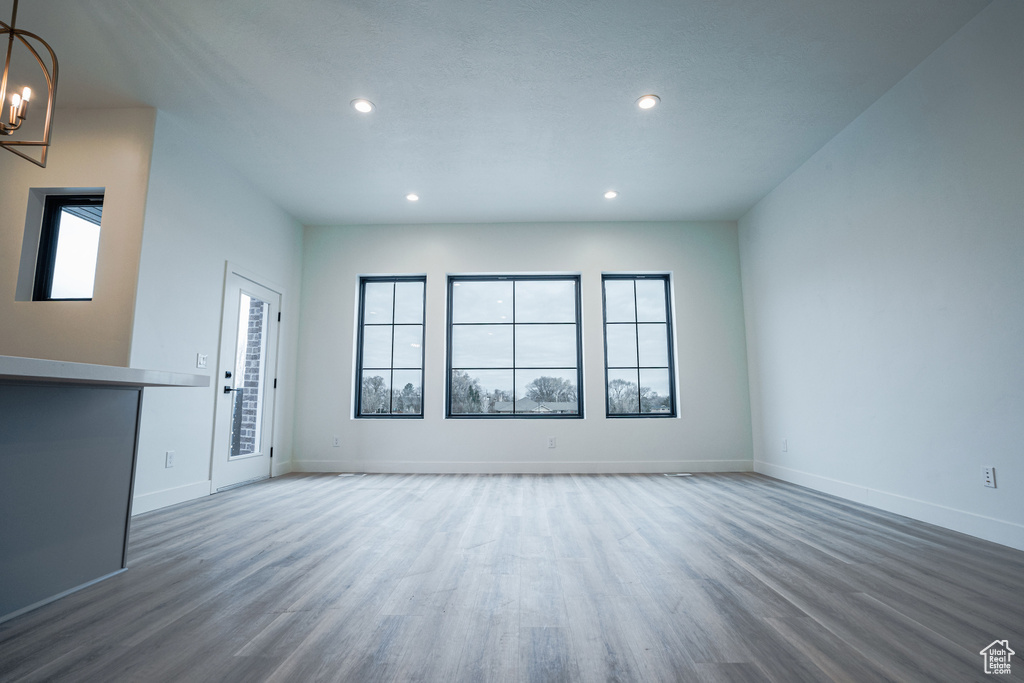 Empty room featuring an inviting chandelier and hardwood / wood-style flooring