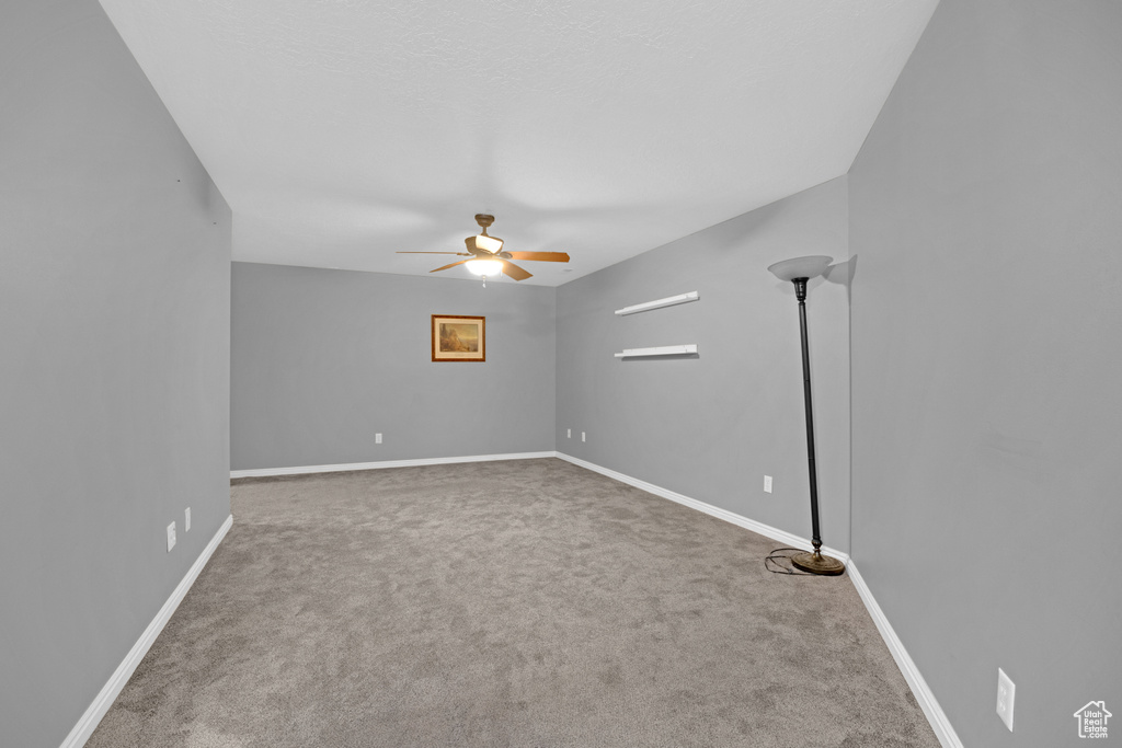 Empty room with dark carpet and ceiling fan