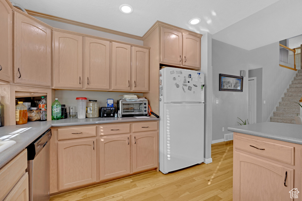 Kitchen featuring light wood-type flooring, white refrigerator, light brown cabinets, and stainless steel dishwasher