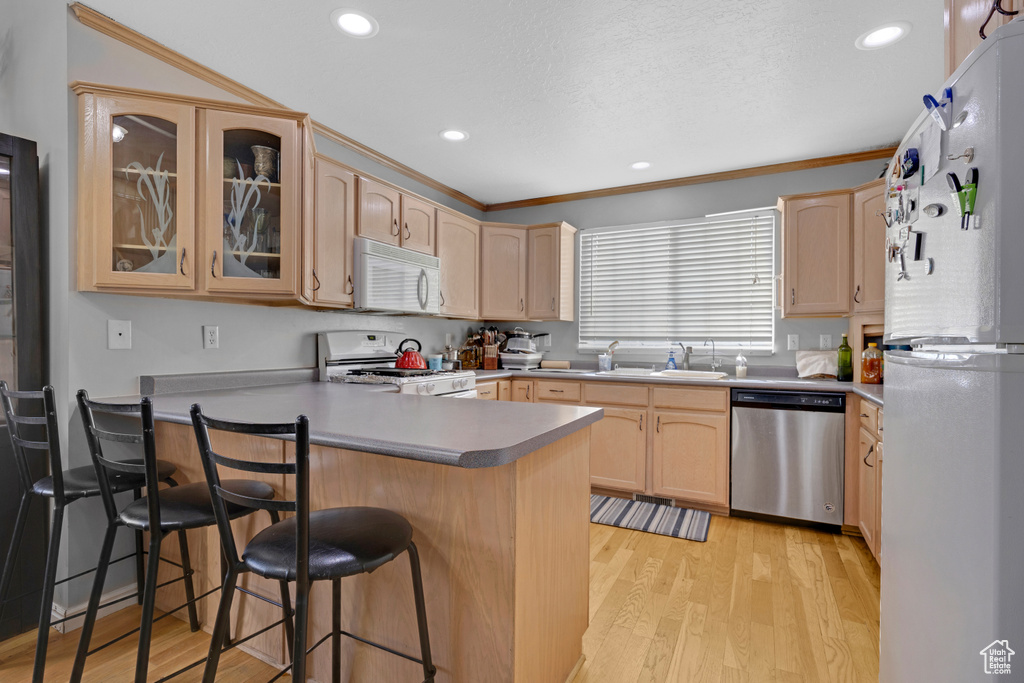 Kitchen featuring ornamental molding, white appliances, and light hardwood / wood-style flooring