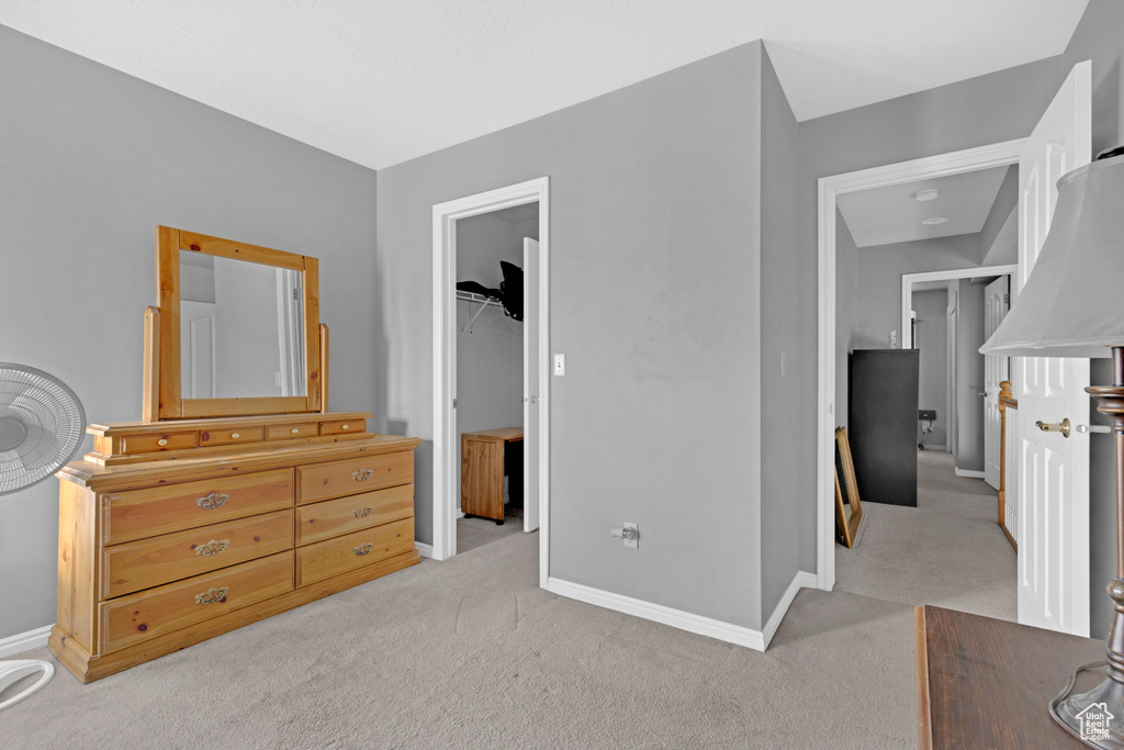 Bedroom with a walk in closet, light carpet, and a closet