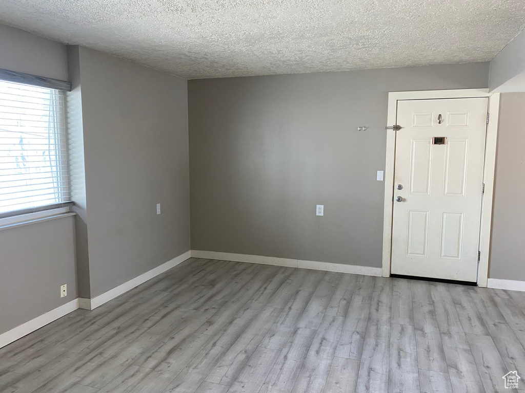 Spare room with a textured ceiling and light hardwood / wood-style floors