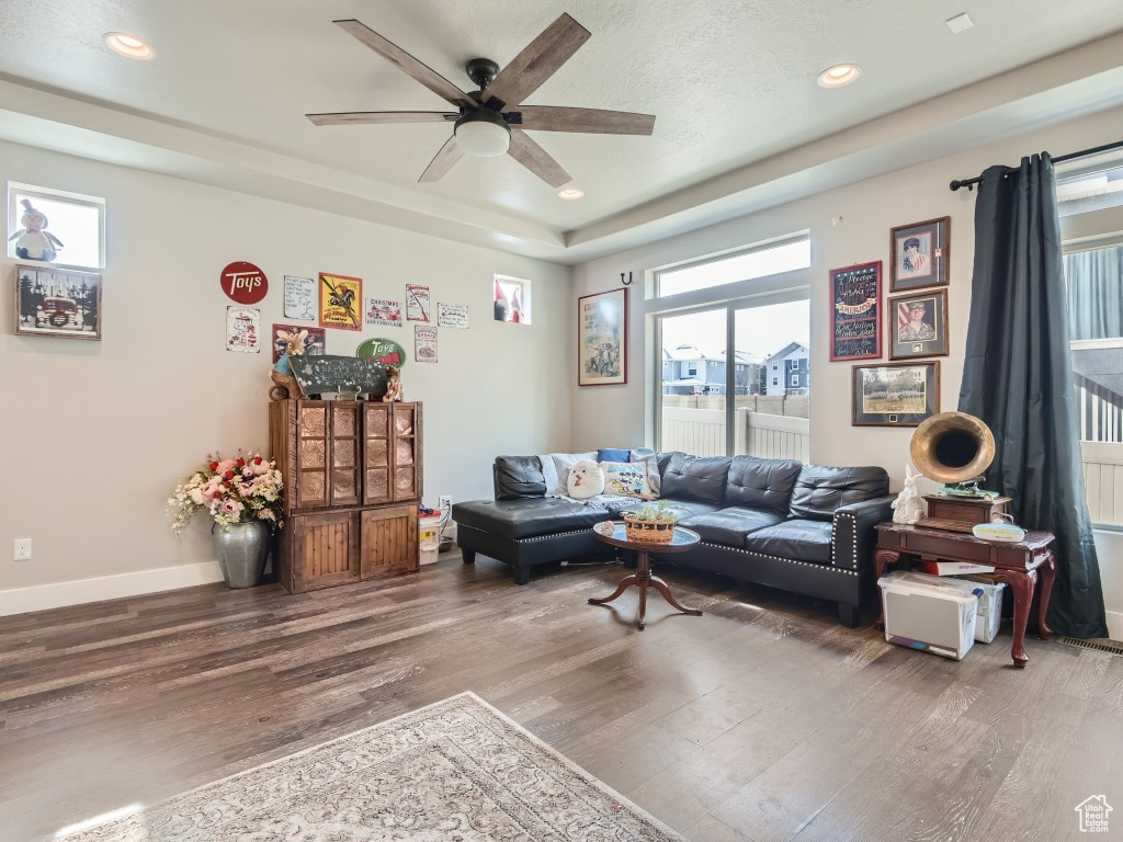 Living room with dark hardwood / wood-style flooring, a wealth of natural light, and ceiling fan