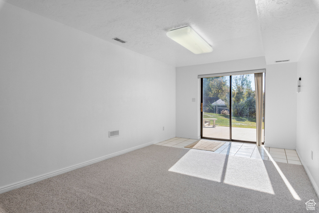 Empty room featuring a textured ceiling and light carpet