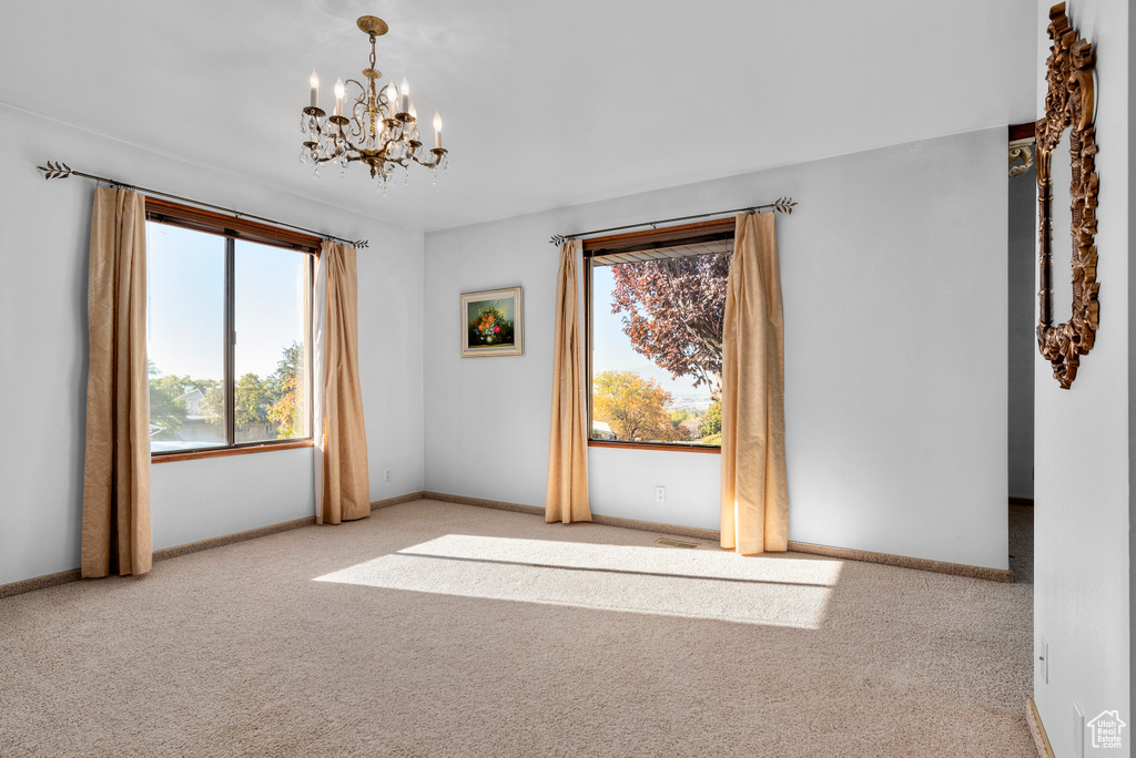Spare room with an inviting chandelier and light carpet