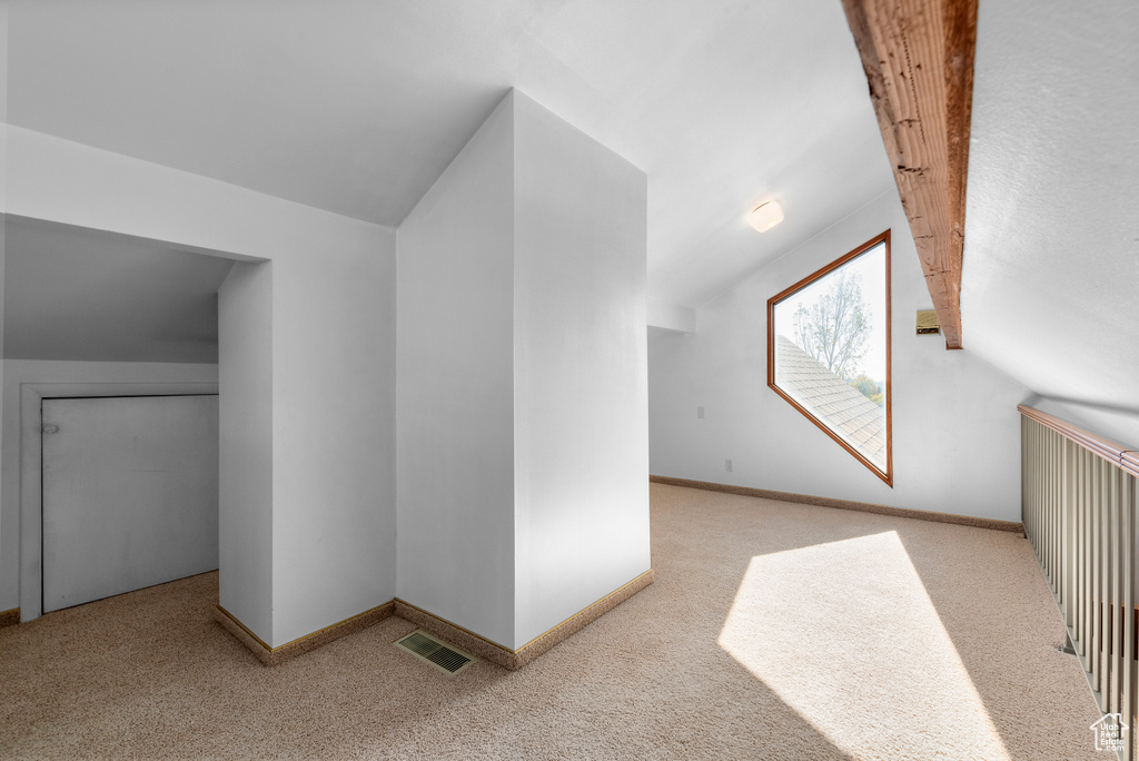 Additional living space with light carpet and lofted ceiling