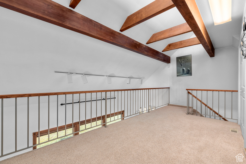 Additional living space with light carpet and vaulted ceiling with beams