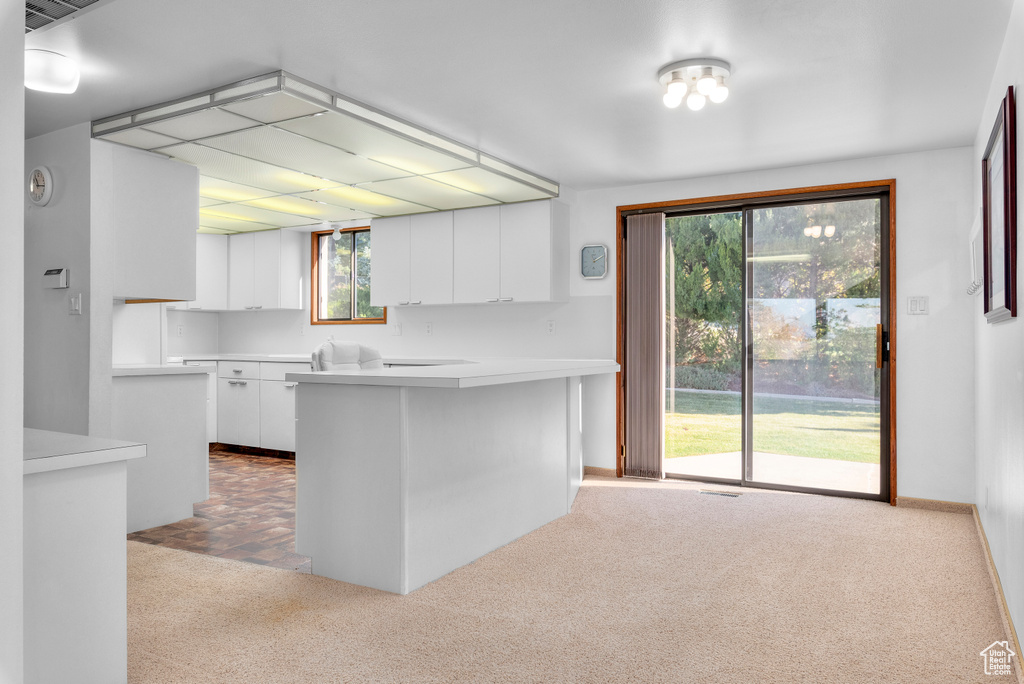 Kitchen featuring white cabinetry and light carpet
