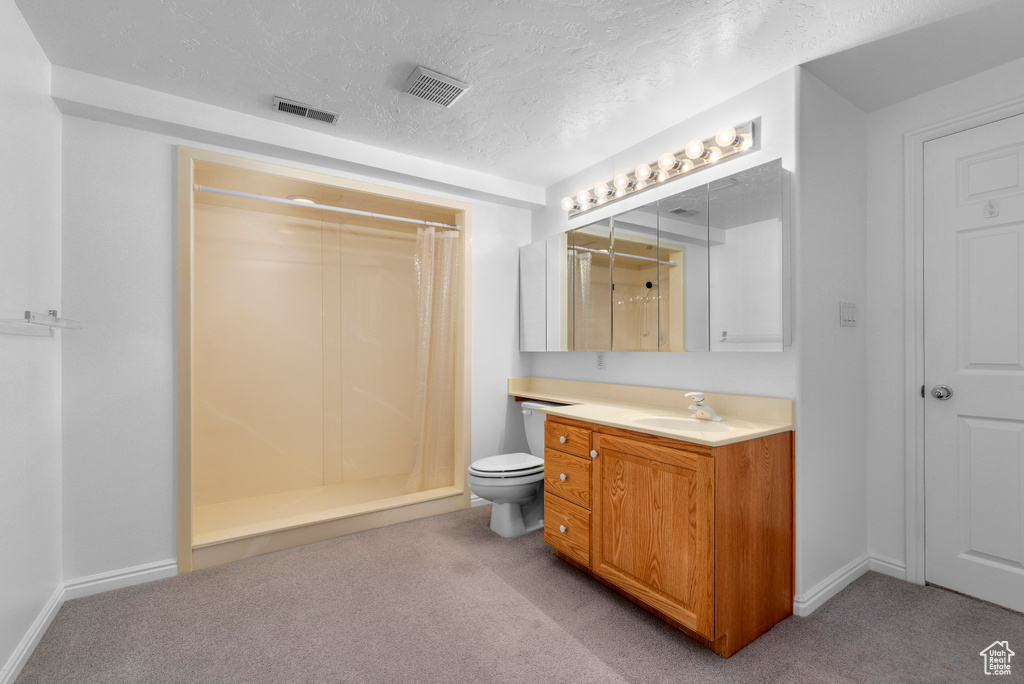 Bathroom with vanity, toilet, a textured ceiling, and curtained shower