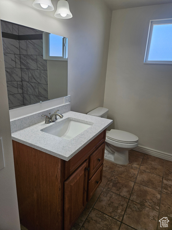 Bathroom with vanity, toilet, a healthy amount of sunlight, and tile floors