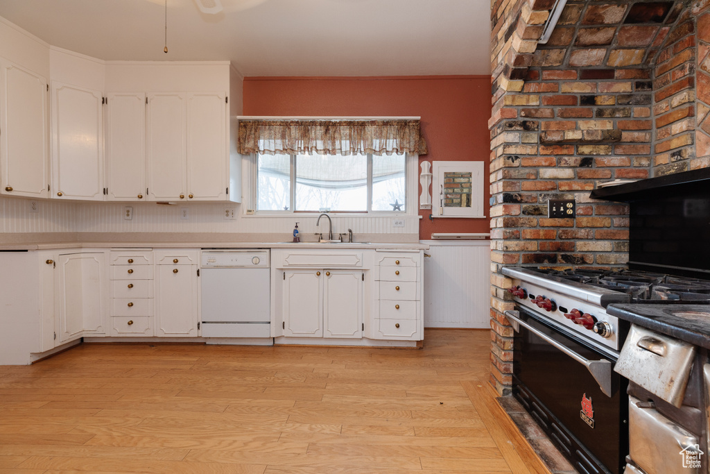 Kitchen with white cabinetry, sink, dishwasher, light hardwood / wood-style flooring, and designer range