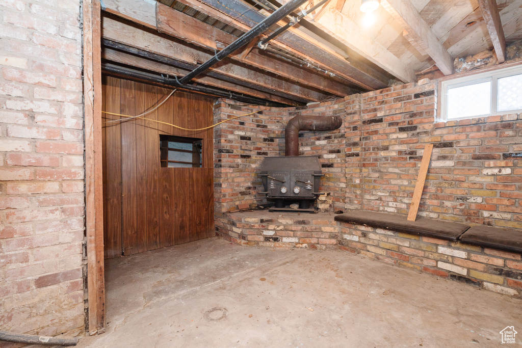 Basement with brick wall, a wood stove, and wooden walls