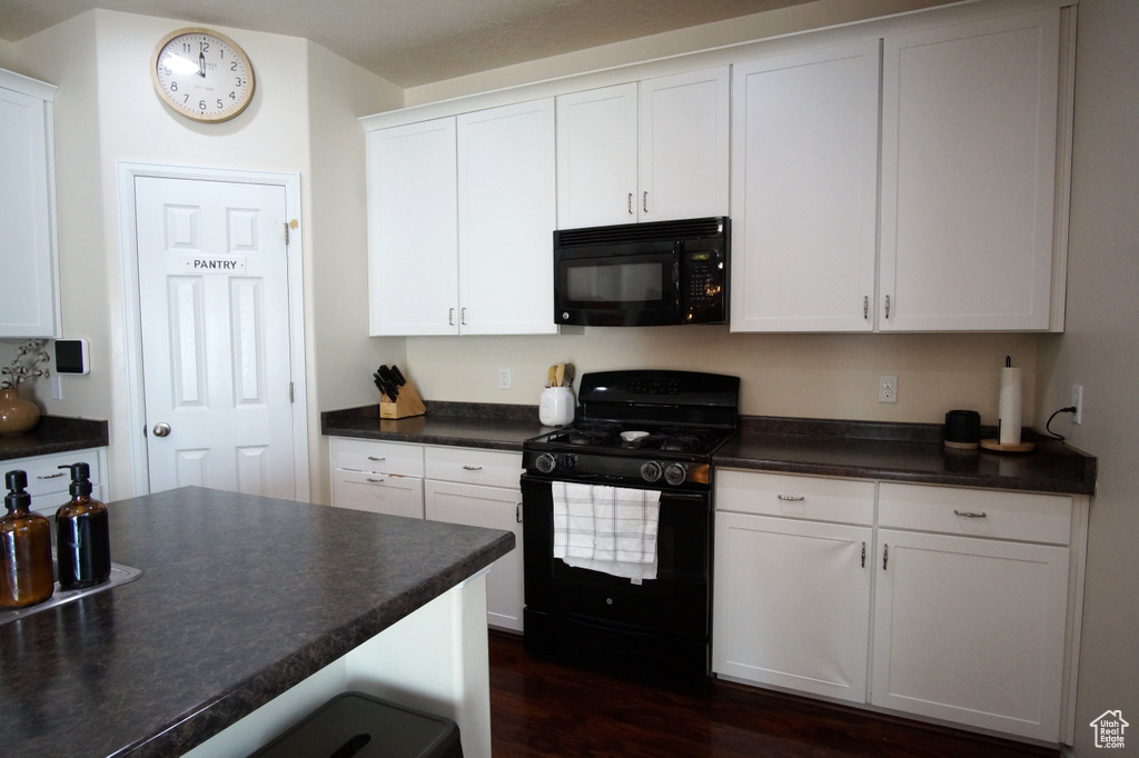 Kitchen with black appliances, white cabinets, and dark wood-type flooring