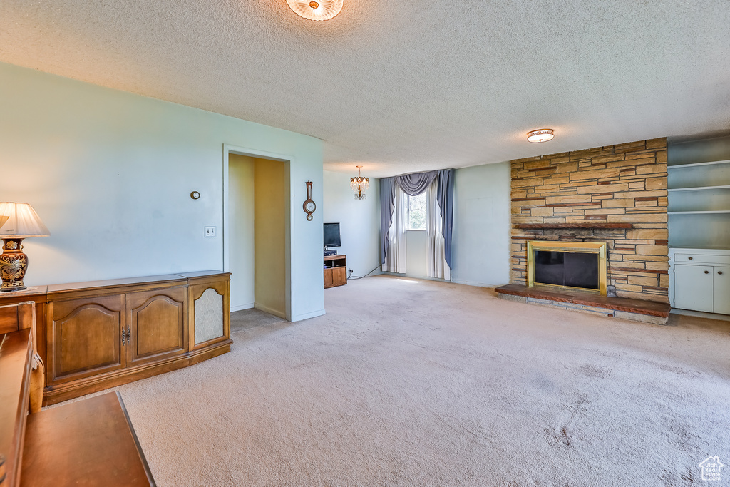 Unfurnished living room featuring light colored carpet, a fireplace, and a textured ceiling