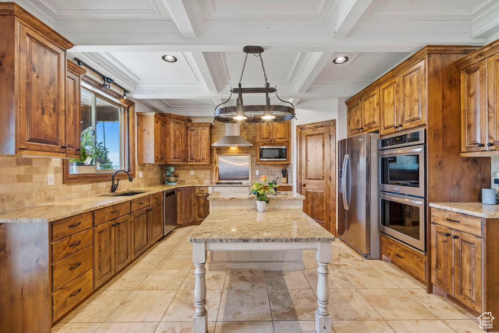 Kitchen featuring tasteful backsplash, appliances with stainless steel finishes, an inviting chandelier, pendant lighting, and wall chimney exhaust hood