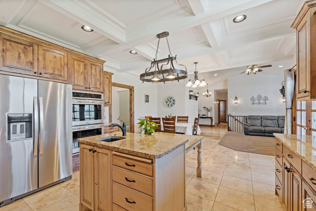 Kitchen featuring sink, appliances with stainless steel finishes, coffered ceiling, a center island with sink, and hanging light fixtures