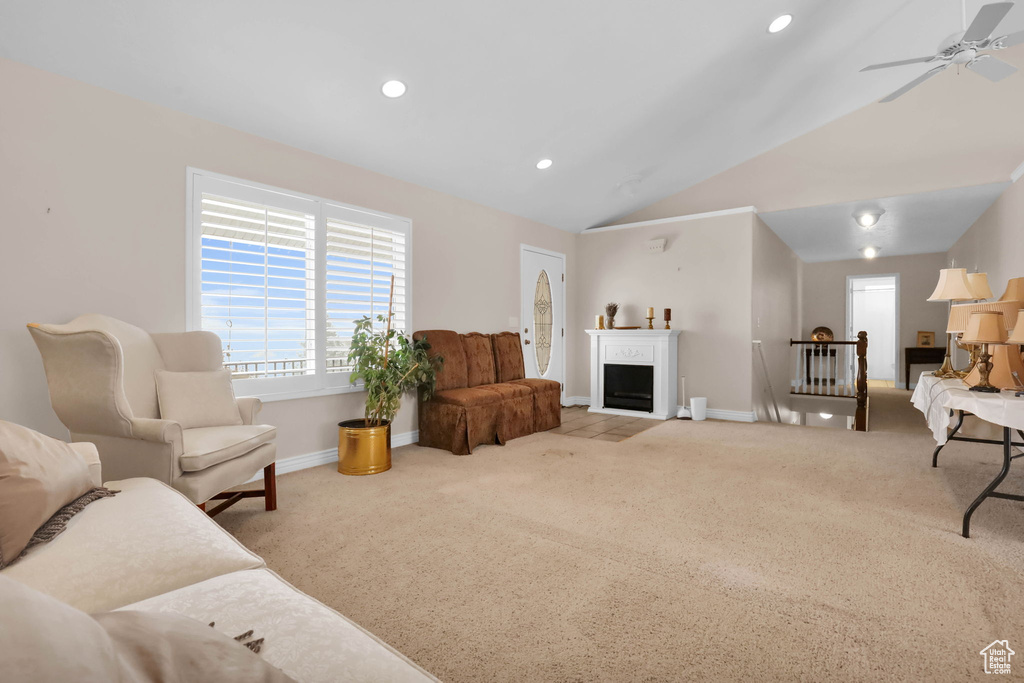Living room featuring vaulted ceiling, ceiling fan, and light carpet