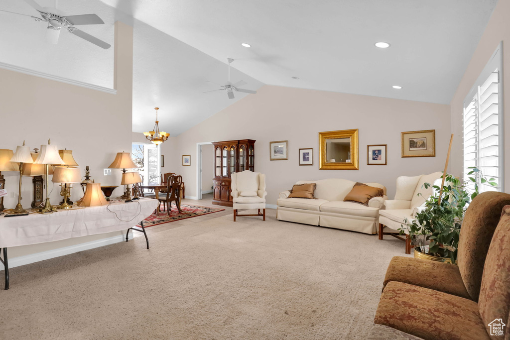 Living room with ceiling fan with notable chandelier, light carpet, and high vaulted ceiling