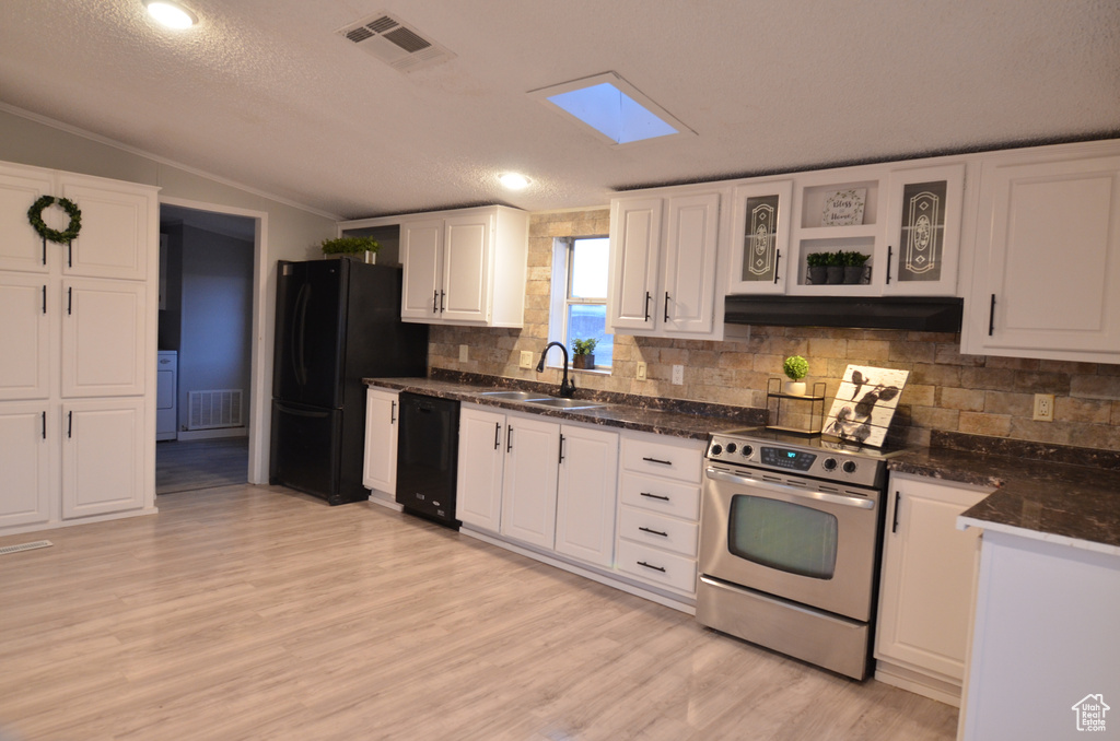 Kitchen with black appliances, sink, light hardwood / wood-style flooring, a skylight, and white cabinetry
