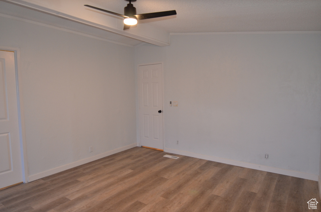 Empty room with hardwood / wood-style flooring, vaulted ceiling with beams, and ceiling fan