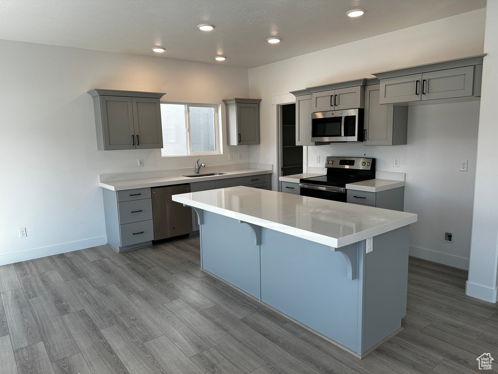 Kitchen with appliances with stainless steel finishes, a kitchen bar, a kitchen island, and gray cabinets