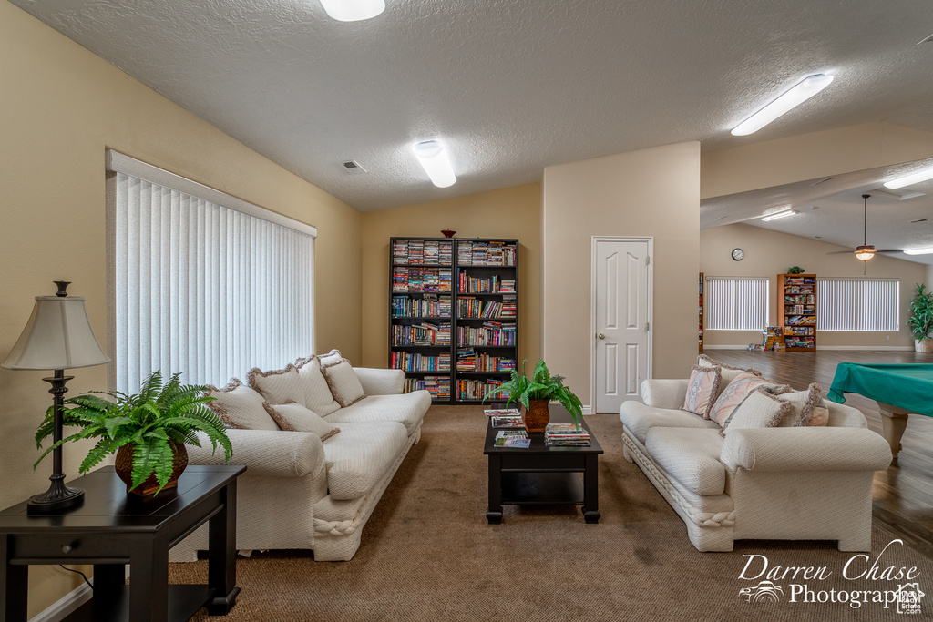 Living room featuring ceiling fan, lofted ceiling, and dark colored carpet