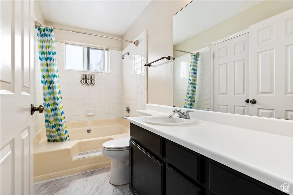 Full bathroom with tile floors, toilet, large vanity, and shower / tub combo