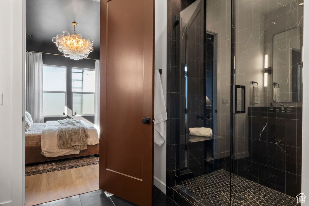 Bathroom with walk in shower, a chandelier, and tile flooring