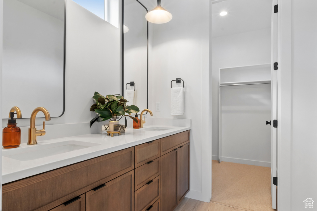 Bathroom featuring dual sinks and vanity with extensive cabinet space