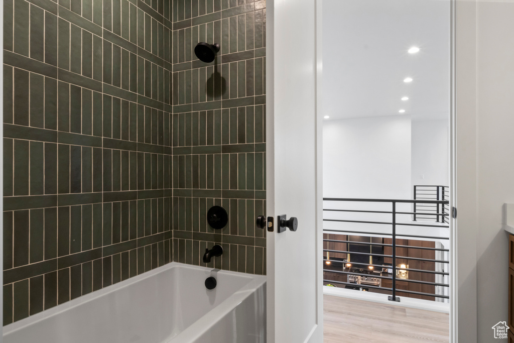 Bathroom featuring a fireplace, wood-type flooring, and tiled shower / bath combo