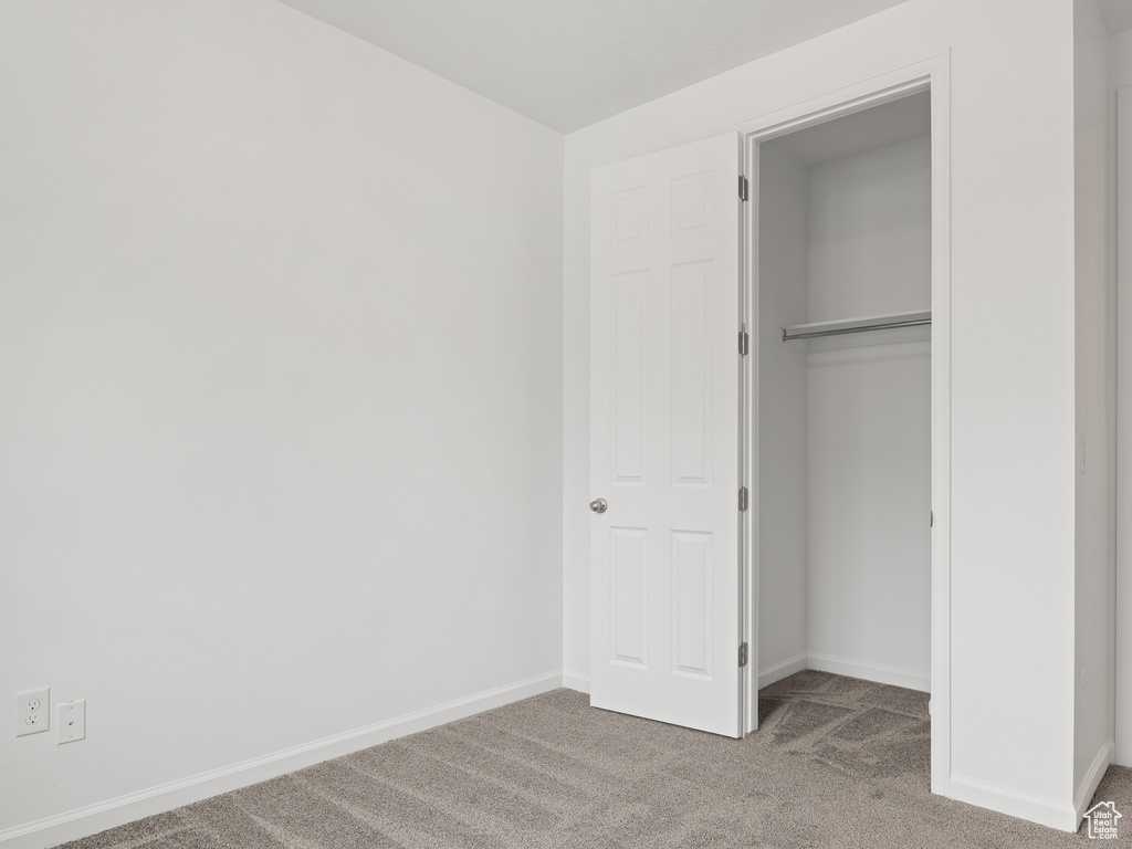 Unfurnished bedroom featuring dark colored carpet and a closet