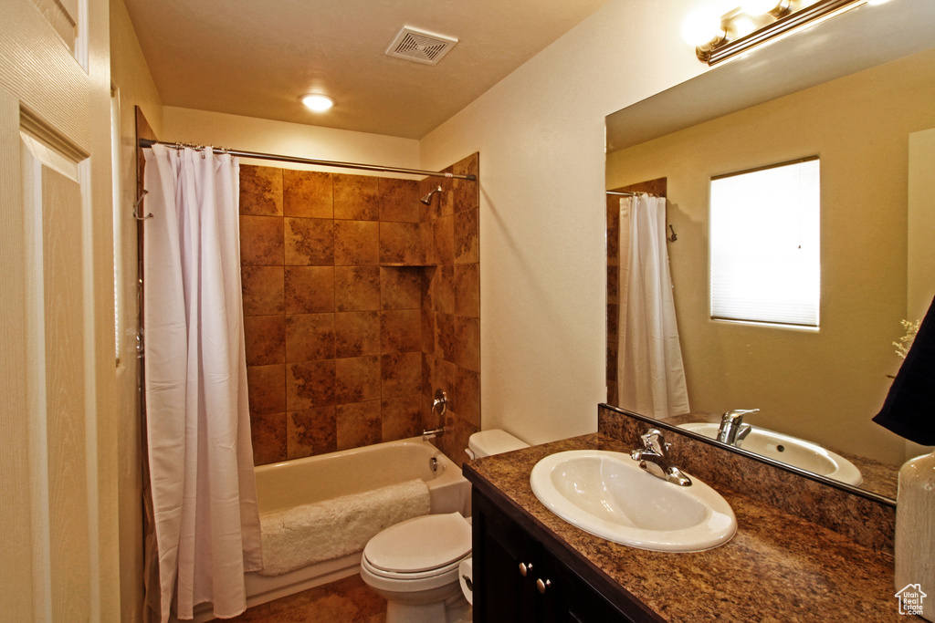 Full bathroom featuring shower / bath combo with shower curtain, toilet, and vanity