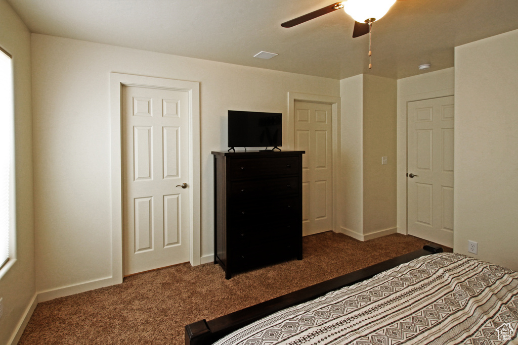Unfurnished bedroom with dark colored carpet and ceiling fan